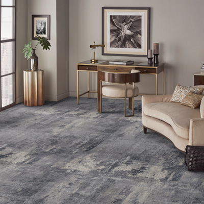 blue patterned carpet in living room with beige couch and desk with maximalist decor.